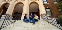 Three college students sitting on the steps outside a campus building
