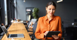Woman in an orange shirt working on a tablet, illustrating CapinCrouse alert about the new Form 8976 submission process.