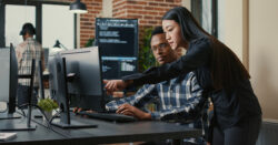 Two colleagues looking at a computer monitor and discussing results, representing this CapinCrouse article about evaluating accounting tech stacks.